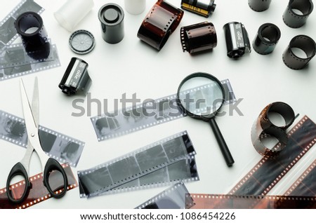 Photographic films, scissors and magnifying glass on white background