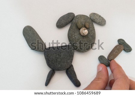 kid's activities with stones on the white background in the school. making dog picture. 