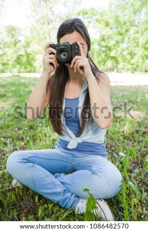 Young Woman Amateur Photographer taking photos with vintage camera in nature