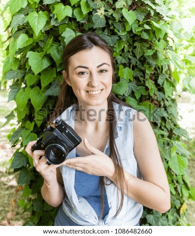 Portrait of Smiling Young Woman Amateur Photographer with vintage camera in the park