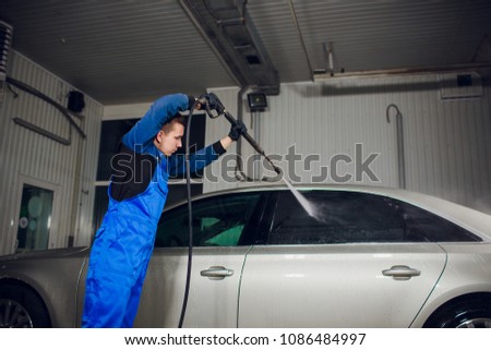 man washing automobile manual car washing self service,cleaning with foam,pressured water. Transportation care concept. Washing car in self service station with high pressure blaster