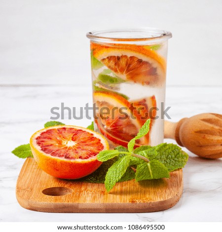 Herbs and fruits flavored infused water with bloody orange. Summer refreshing drink. Health care, fitness, healthy nutrition diet concept.