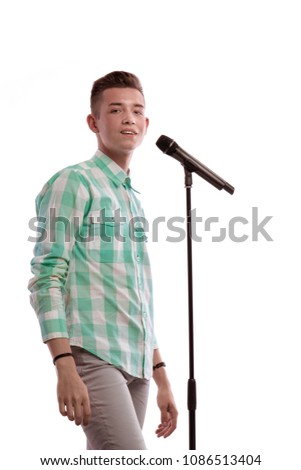 Portrait of a young guy in a light shirt with a microphone in his hands sings a song and posing against a white background
