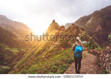 Girl walking down along the trekking route to verdant Xo-Xo valley. Warm sunlight seable on horizont. Santo Antao Island Cape Verde Royalty-Free Stock Photo #1086515954