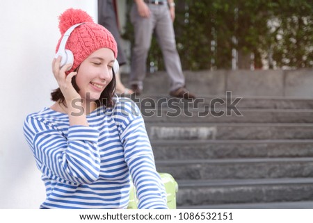 Young happy caucasian teenager listening to music while sitting in city, young traveler in headphones relax with music after walking all day, lifestyle recreation time in weekend concept