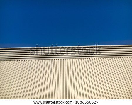Steel sheet siding of the building with blue sky background.