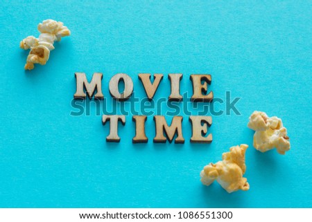 Text "Movie Time" and popcorn on blue background. Flat lay, Top view. 