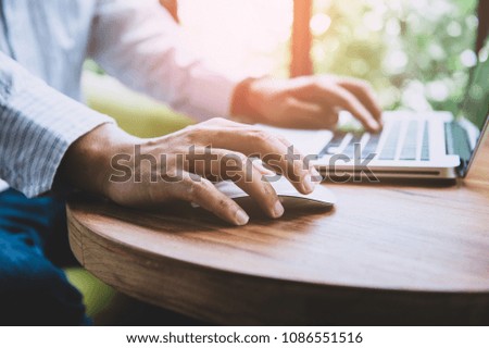 Business man  hands using laptop with blank screen on desk in cafe. instagram style filter photo vintage tone