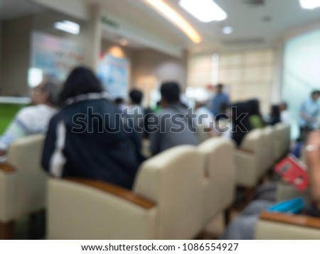 The blurred picture is many people are in hospital. They are waiting for get the medicine and sitting on white sofa.