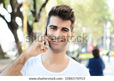 Portrait of young man talking on the phone. Outdoors.