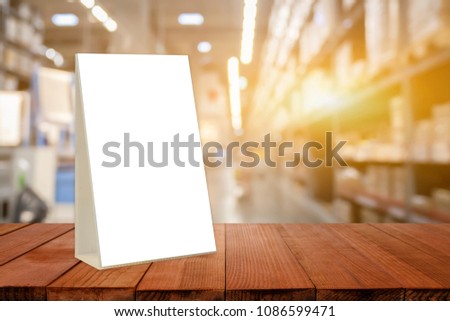 acrylic tent card on Empty brown wooden table  shop interior with Mock up Menu frame in shopping mall,Stand for booklets with white sheets of paper  on business market blurred background