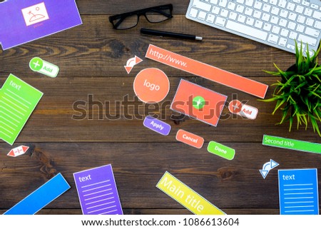 Web design concept. Site elements on office desk on dark wooden background top view copy space