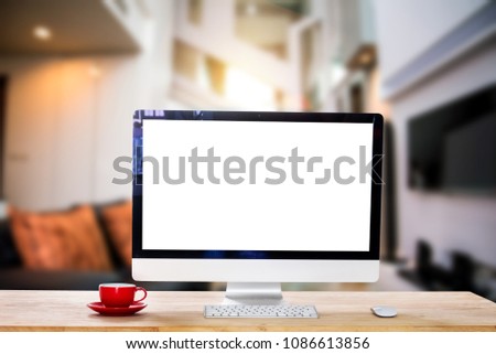 Workspace with computer Monitor, Keyboard,blank screen coffee cup on a table in bright office room interior.
