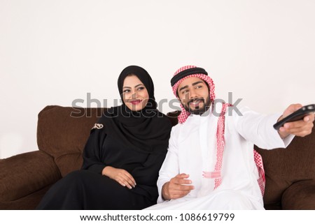 Arab couple watching TV at home with white background