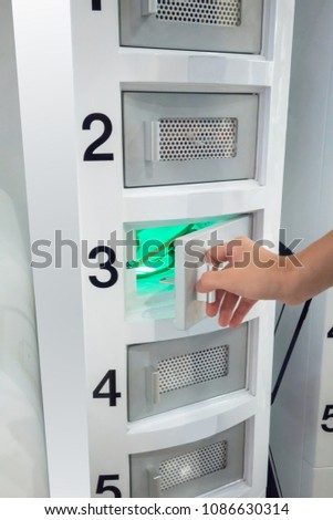 Hand opening the door of smart phone charger tower in shopping mall