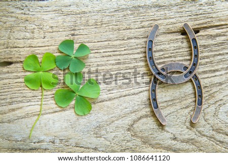 Horse shoe and four leaf clover on old wood background