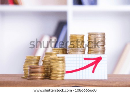 coins stacked on the table with arrow graphic. concept of savings and economy