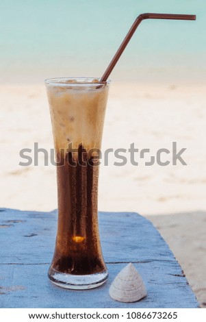 Ice coffee on wooden table with blue sea background