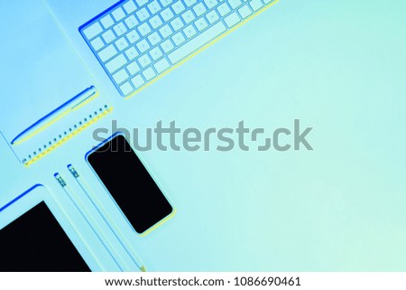 blue toned picture of pencils, textbook, pen, digital tablet, smartphone and computer keyboard 