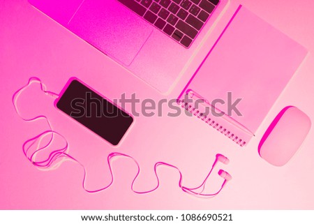 pink toned picture of laptop, empty textbook, pencil, smartphone, earphones and computer mouse 