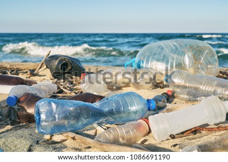 Spilled garbage on the beach of the big city. Empty used dirty plastic bottles. Dirty sea sandy shore the Black Sea. Environmental pollution. Ecological problem. Bokeh moving waves in the background  Royalty-Free Stock Photo #1086691190