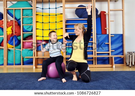 Woman as a therapist at physiotherapy with medicine ball with child in gym Royalty-Free Stock Photo #1086726827