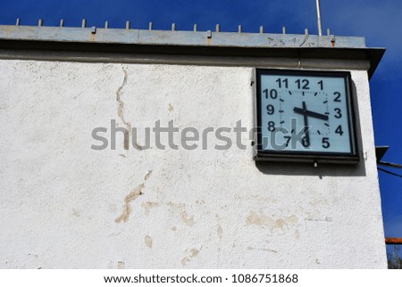 Old shabby wall with square clocks on blue sky background