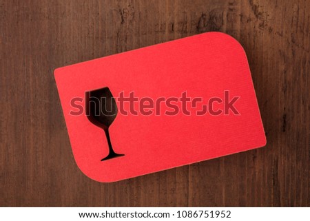 An overhead photo of a stack of laser cut red business cards with a wineglass
