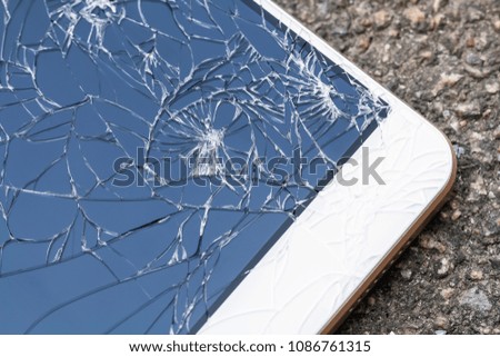 Smartphone with broken blue display screen is lying on the asphalt. Closeup, selective focus