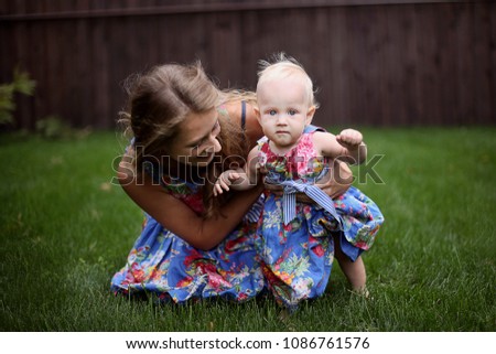 Family. Portrait of beautiful cheerful mother with her cute daugher having fun together outdoors. Smiling girl with mom 