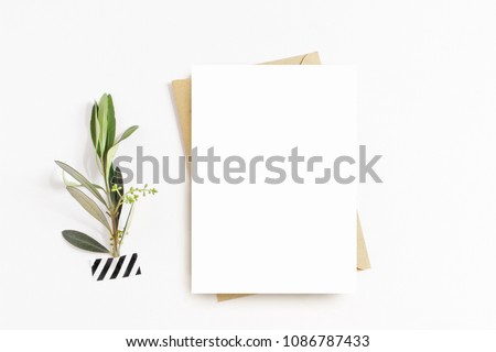 Feminine stationery, desktop mock-up scene. Blank greeting card, craft envelope, washi tape and with olive branch.White table background. Flat lay, top view. 