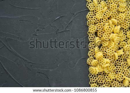 Raw ruote Beautiful decomposed pasta with the right, on its side on a black textured background. Close-up view from the top. Free space for text.