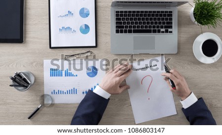 Business person drawing question mark on business plan, lack of ideas, top view