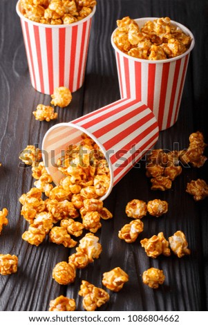 three striped boxes of sweet caramel popcorn close-up on wooden background. Vertical
