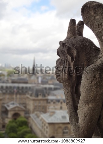 photo of gargoyle in Notre Dame - Paris. the gargoyleis watching over the people and think about the amazing beauty of this city. Tour Eiffel on background
