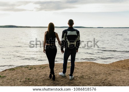 couple standing on the beach and watching the sunset
