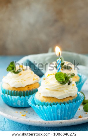 Orange Birthday cupcake with buttercream icing and candle on a blue a stone or slate background. Copy space.