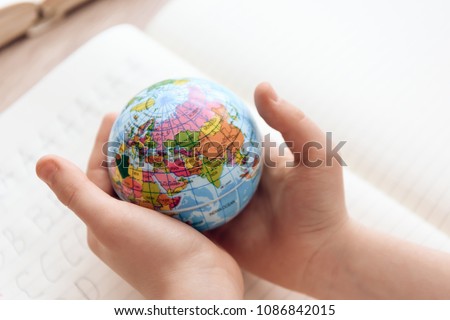 Close up. Child holds small globe in hands. Studies of geography. Self education concept. Royalty-Free Stock Photo #1086842015