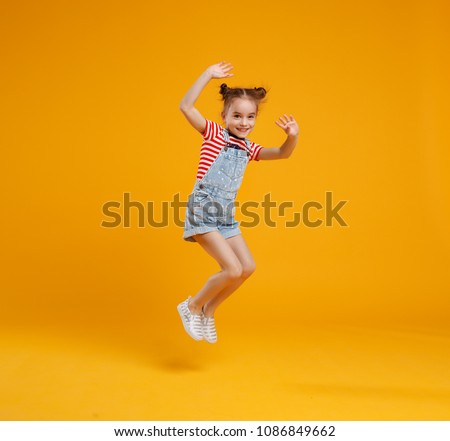 funny child girl jumping on a colored yellow background
