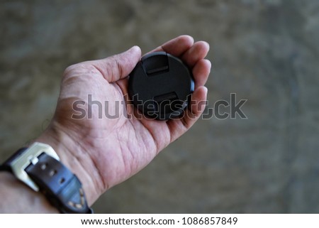 Travel trip photographer give lens cap in hand.journey concept.Hand holding lens or camera cap 