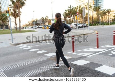 Back view picture of amazing young asian sports woman running outdoors.