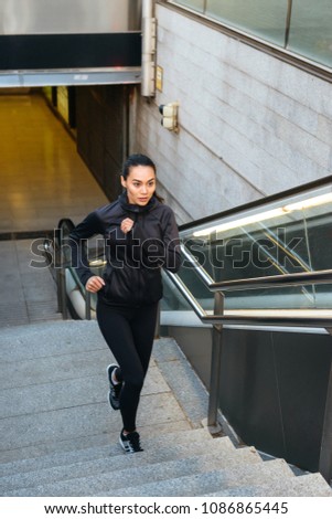 Photo of amazing concentrated young asian sports woman running on steps outdoors.