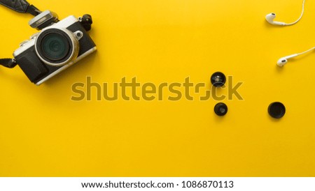 camera and earphone with small lend  on yellow background travel concept