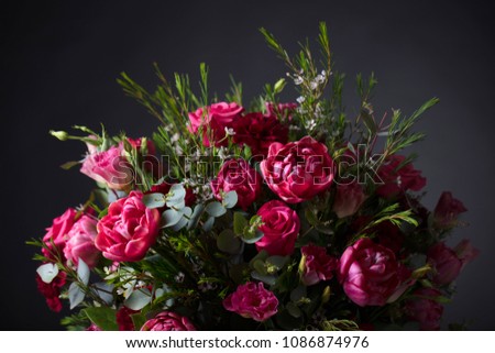 Close up of colorful spring flowers bouquet with red roses and peonies on black background.