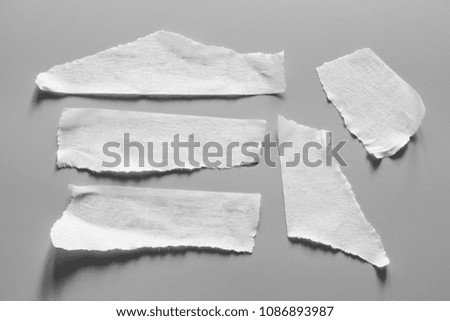 Set of white tapes on gray background. Torn horizontal and different size black sticky tape, adhesive pieces.
