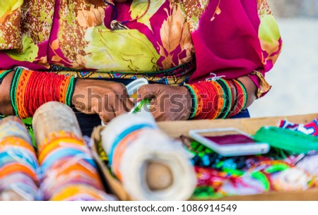 A view of an indigenous Kuna lady wearing traditional mola clothing making traditional chaquiras. Royalty-Free Stock Photo #1086914549