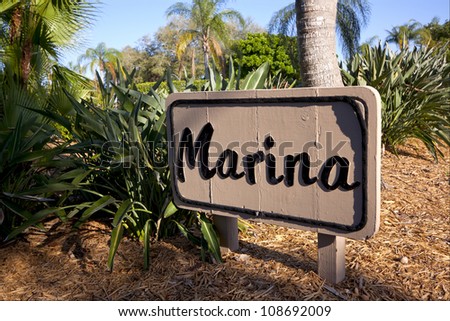 A directional sign that reads Marina surrounded by palm trees.