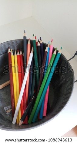 The wooden color pencil with the pencil sharpener in aluminium container on white blackground.
