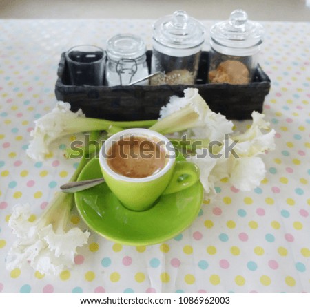 A cup of green coffee and white flowers are placed on the table.