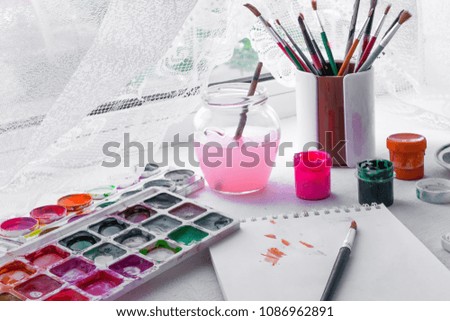 Artistic brush, paint gouache, watercolor, palette paper for painting, various accessories for a hobby artist on a light background near a window with a copy space